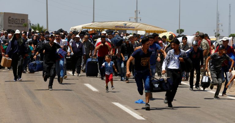 Syrians, who say they are returning to Syria ahead of the Eid al-Fitr, carry their belongings as they walk to the Turkish Cilvegozu border gate, located opposite of Syrian crossing point Bab al-Hawa in Reyhanli, in Hatay province