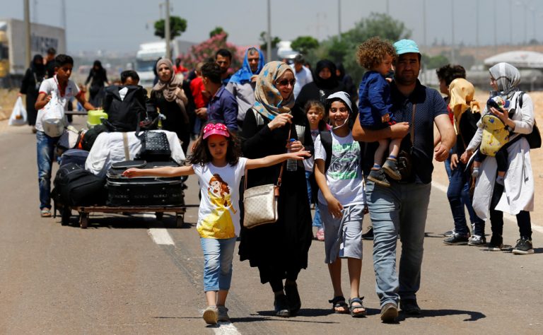 Syrians, who say they are returning to Syria ahead of the Eid al-Fitr, carry their belongings as they walk to the Turkish Cilvegozu border gate, located opposite of Syrian crossing point Bab al-Hawa in Reyhanli, in Hatay province