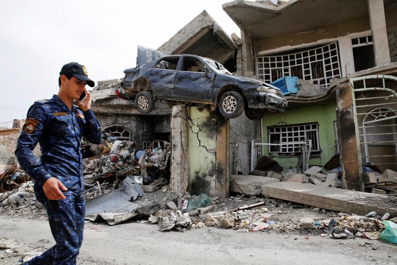 A member of the Iraqi Federal Police walks next to a destroyed house after their clashes with the Islamic State fighters in western Mosul